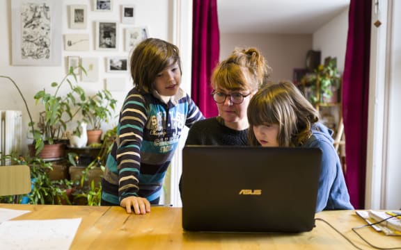 Fanny Delque, centre, helps her children, Flora and Mathias do their schoolwork at home in Mulhouse, eastern France. as schools close to try to curb the spread of coronavirus.