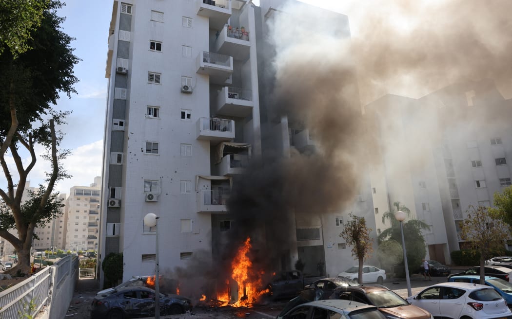 Cars parked outside a residential building catch fire during a rocket attack from the Gaza Strip on the southern Israeli city of Ashkelon, on October 7, 2023. Palestinian militants have begun a "war" against Israel, the country's defence minister said on October 7 after a barrage of rockets were fired and fighters from the Palestinian enclave infiltrated Israel, a major escalation in the Israeli-Palestinian conflict. (Photo by AHMAD GHARABLI / AFP)