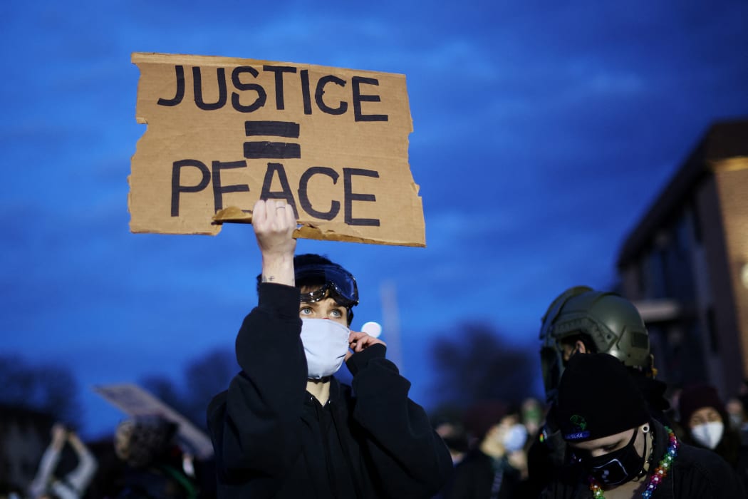 A demonstrator holds up a sign during a protest outside the Brooklyn Center police station on 17 April, in Brooklyn Center, Minnesota.