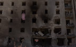 A woman cleans debris in an apartment in a heavily damaged residential building following a Russian aerial attack, in Selydove, the eastern Donetsk region on June 27, 2024, amid the Russian invasion of Ukraine. (Photo by Roman PILIPEY / AFP)