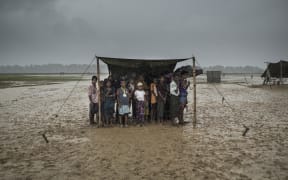 (FILES) In this file photo taken on October 6, 2017 Rohingya refugees take shelter from the rain at Nayapara refugee camp in Bangladesh's Ukhia district.