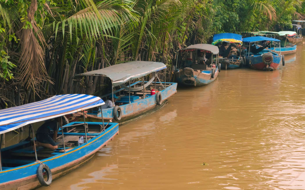 Tour boats moored on a tributary of the Mekong River near My Tho, Vietnam.
