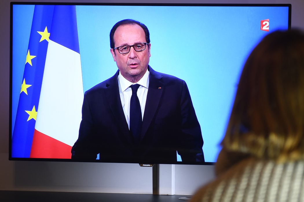 A person watches Francois Hollande's televised announcement that he will not seek a second term.