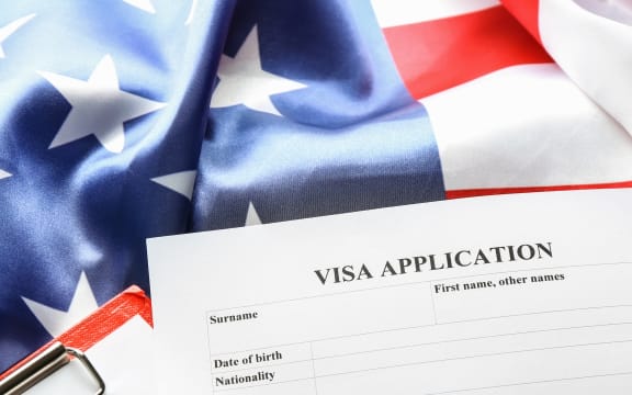 Passports, American flag and visa application form on table. Immigration to USA.