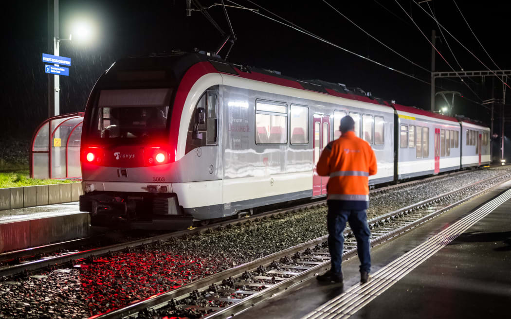 A railway technician stands next to a train, where passengers travelling from Yverdon to Sainte-Croix were earlier held hostage, in Essert-Sous-Champvent, western Switzerland, on 9 February, 2024. A hostage situation on a train in the west of Switzerland ended with the suspect killed in a police raid and the hostages safely freed, authorities said. (Photo by Fabrice COFFRINI / AFP)