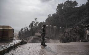 A rescue personnel searches for villagers in an area covered in volcanic ash at Sumber Wuluh village in Lumajang.