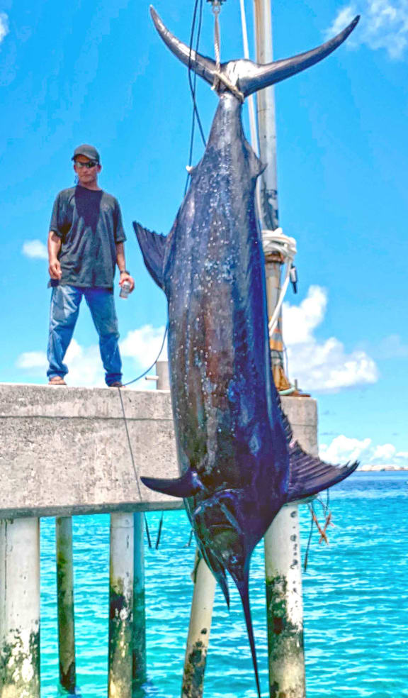 Marshall Islands angler Bwiji Aliven stands on the dock next to his mammoth marlin catch, which weighed in at 429kg.