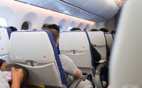 Man asleep in seat on airplane during travel abroad in aircraft.