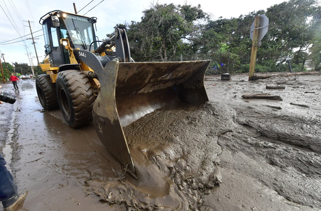 A bulldozer clears mud off the road near a flooded section of US 101 freeway near the San Ysidro exit in Montecito, California.