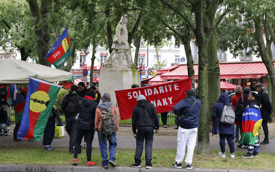 Protestors take part in a demonstration led by the Union of Kanak Workers and the Exploited (USTKE) and organisations of the Kanaky Solidarity Collective in support of Kanak people, with flags of the Socialist Kanak National Liberation Front (FLNKS) next to a statue of Vauban, amid a debate at the French National Assembly on the constitutional bill aimed at enlarging the electorate of the overseas French territory of New Caledonia, in Paris on May 14, 2024. France's prime minister on May 14, 2024, urged the restoration of calm in New Caledonia after the French Pacific archipelago was rocked by a night of rioting against a controversial voting reform that has angered pro-independence forces.