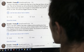 This illustration photo shows an editor in Los Angeles looking at the official Twitter account of US President Donald Trump on May 26, 2020, with two tweets by the president under which Twitter posted a link reading "Get the facts about mail-in ballots".