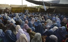 Women with their children wait to receive a food donation from the Afterlife foundation during Ramadan in Kandahar on April 27, 2022.