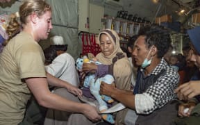 CPL Toni Thompson loads families as they board a NZ Defence Force Hercules in Palu. The evacuees were taken to Balikpapan airport.