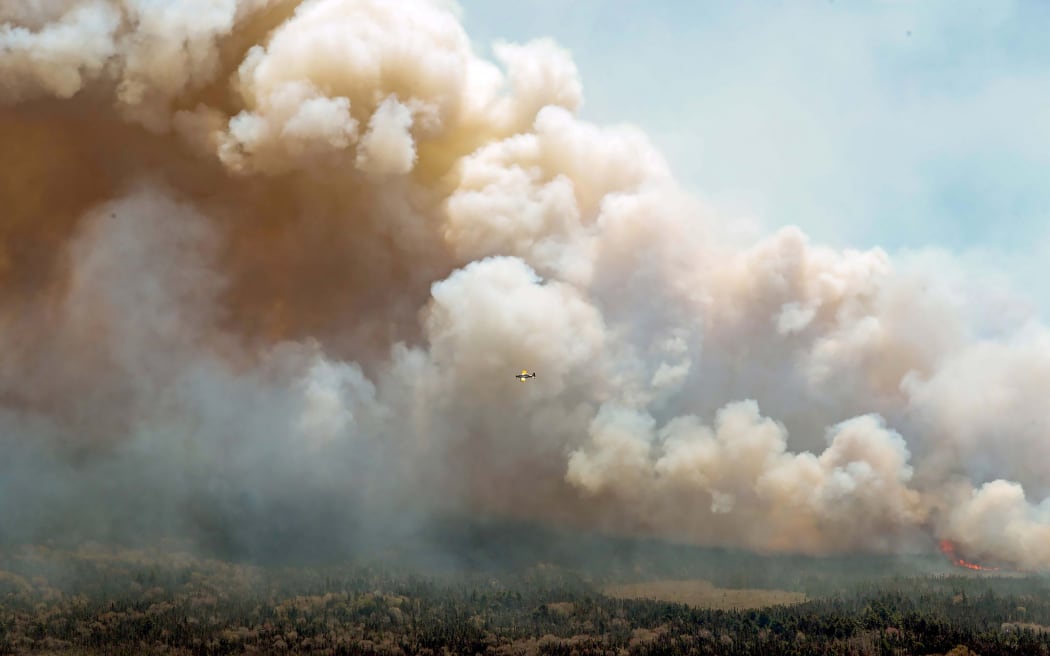 This May 31, 2023, image courtesy of the Nova Scotia Government in Canada, shows one of eight aircraft from New Brunswick that drops a mix of water and fire retardant making a pass over the fire near Barrington Lake, Shelburne County.