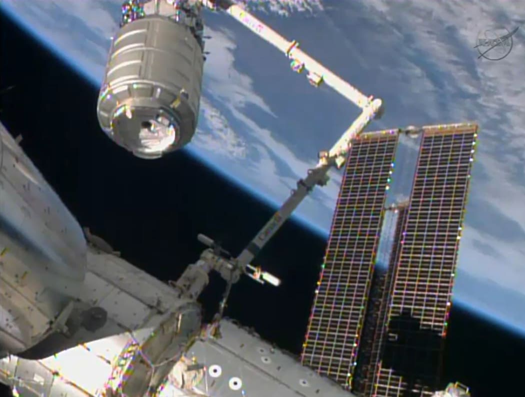 The Cygnus cargo ship (top left) being captured by a robotic arm and brought to the International Space Station on Sunday.