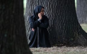 A woman sits quietly across the road from the Masjid Al Noor mosque.