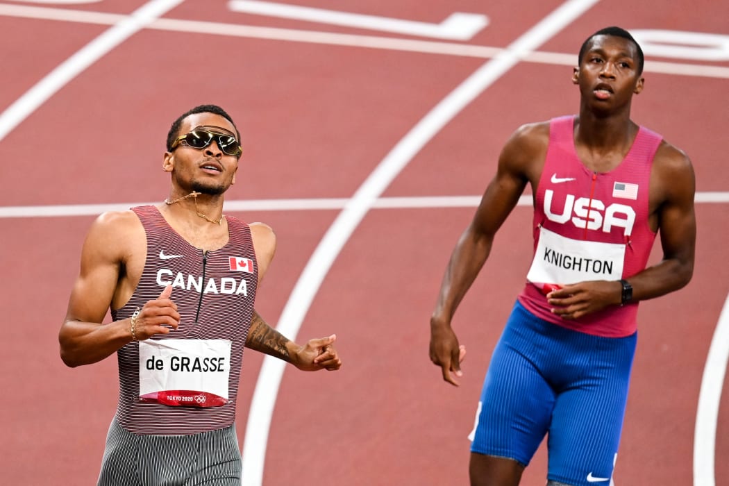 Gold medal winner Andre de Grasse of Canada alongside Erriyon Knighton of the United States cross the finish line in the men's 200m final during the athletics event at the Tokyo 2020 Olympic Games.