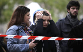People gather at a cordon close to the Bataclan theatre where flowers and messages have been left the day after a series of attacks left dozens dead.