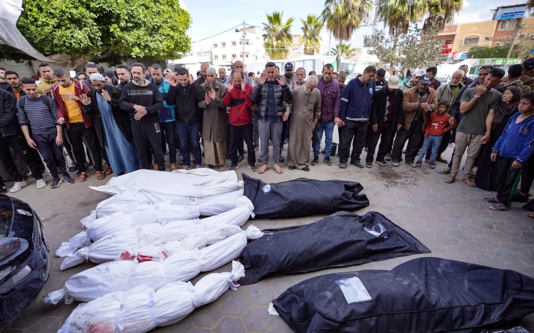 Palestinians recite a prayer over bodies of persons killed in Israeli bombing in Deir el-Balah in the central Gaza Strip before their burial on March 14, 2024.