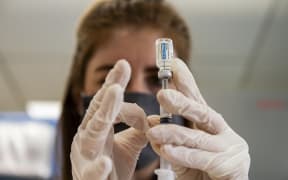 (FILES) In this file photo taken on March 4, 2021 Home base primary care Pharmacist Erin Emonds logs onto a computer before filling syringes the Johnson & Johnson Janssen vaccine  in Boston, Massachusetts.
