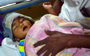 An Indian man holding his baby suffering from malaria at an emergency ward at a children's hospital in Allahabad. September 3, 2015.