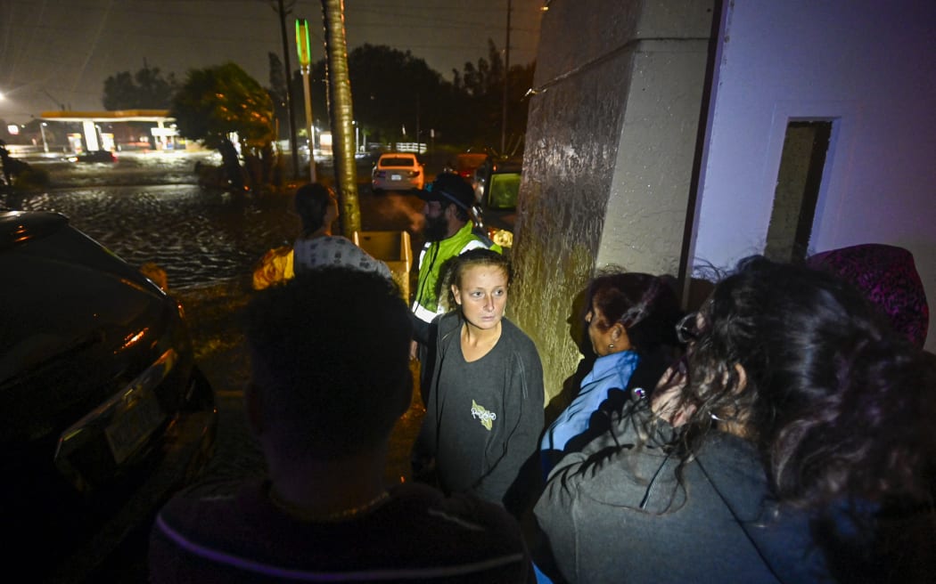People watch water-flooded streets after Hurricane Milton made landfall in Brandon, Florida on October 9, 2024. - Milton made landfall in Florida October 9, 2024 as an "extremely dangerous" Category 3 hurricane, packing life-threatening storm surge, extreme winds and flash flooding, the National Hurricane Center (NHC) said. "Data indicate the eye of Hurricane Milton has made landfall near Siesta Key in Sarasota County along the west coast of Florida," the NHC said in an 8:30 pm (0030 GMT Thursday) bulletin. (Photo by Miguel J. Rodriguez Carrillo / AFP)