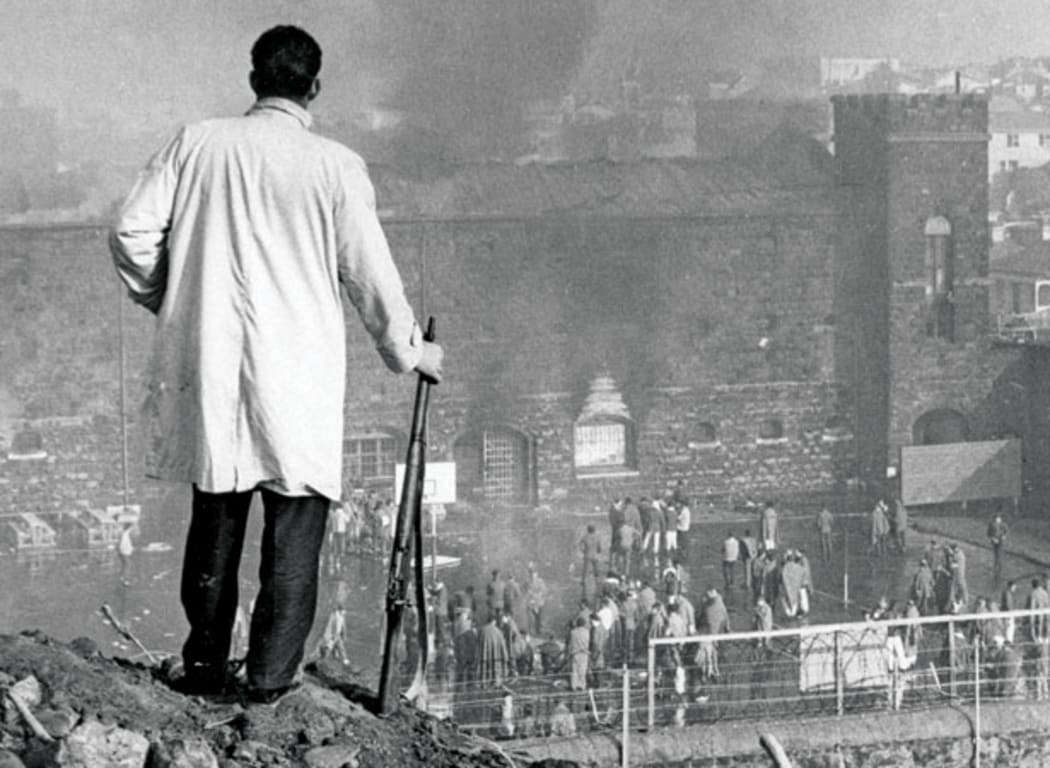 An armed offenders’ squad officer watches the riot.