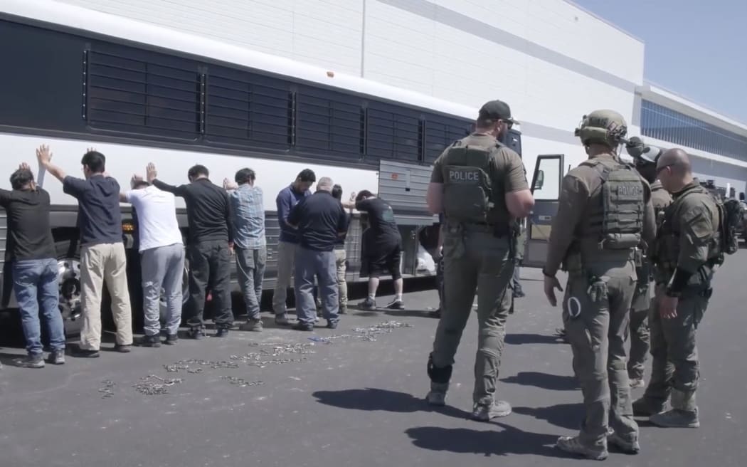 This image from video provided by US Immigration and Customs Enforcement shows manufacturing plant employees waiting to have their legs shackled at the Hyundai Motor Group’s electric vehicle plant, in Ellabell, Georgia, on September 4.