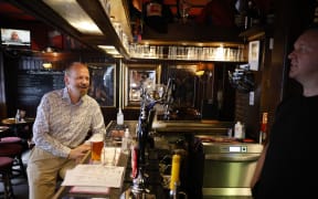 A customer drinks a pint standing at the bar of a pub in central London on July 19, 2021 as coronavirus restrictions are lifted.