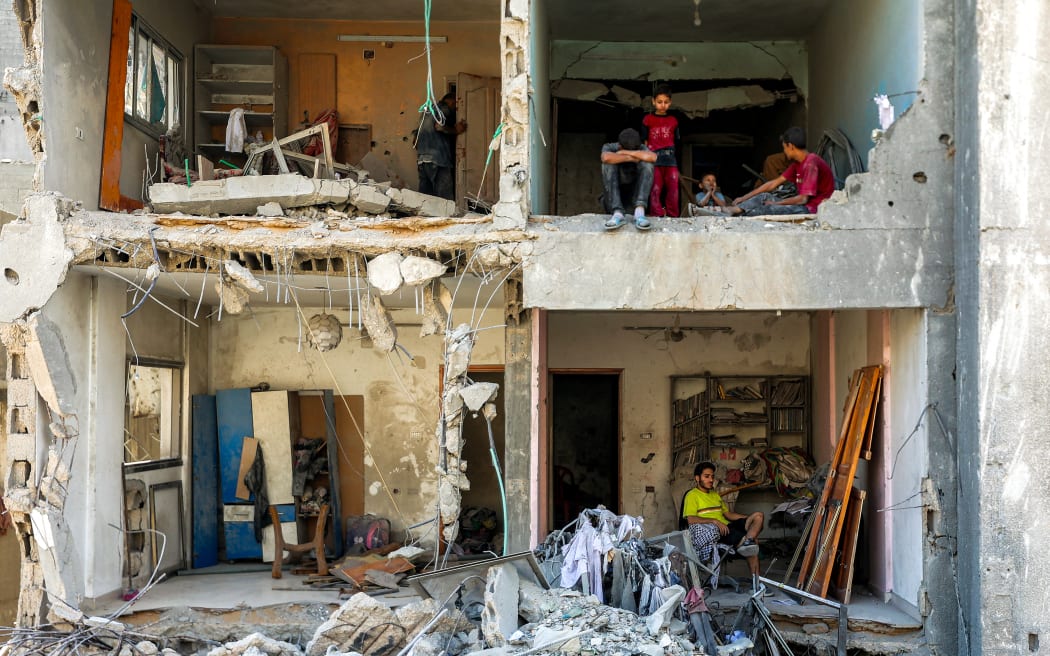 A man and children sit in exposed rooms in a heavily damaged building near the Unknown Soldier Tower, which was destroyed by overnight Israeli bombardment, in the Rimal neighbourhood of Gaza City.