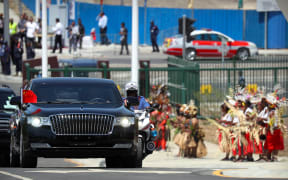 A limousine carrying China's President Xi Jinping drives past dancers in traditional attire. Port Moresby, November 16, 2018.