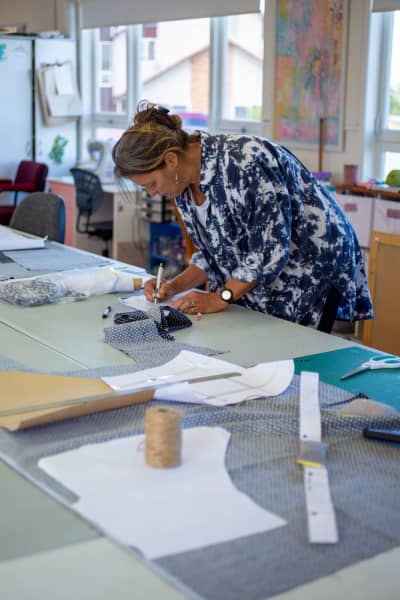Raft Studios founder Jen van der Woerd using a ruler on a table with a pattern and fabric.
