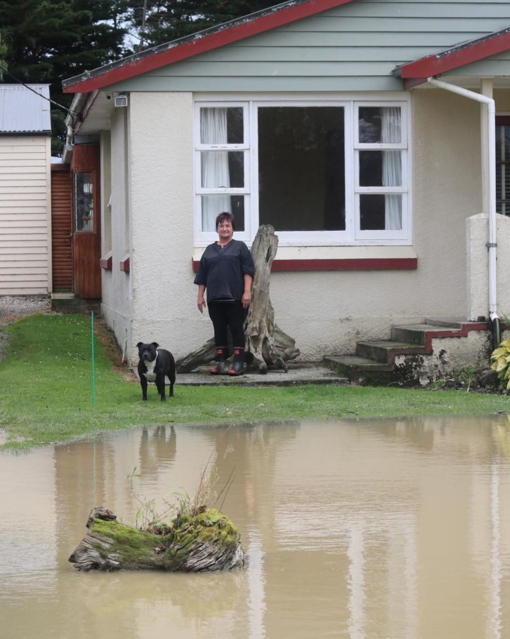 Near the Wyndham bridge, Sue Campbell's driveway has been ripped up by the force of the water that came over it. The flooding reached the porch where she is standing before receding.
