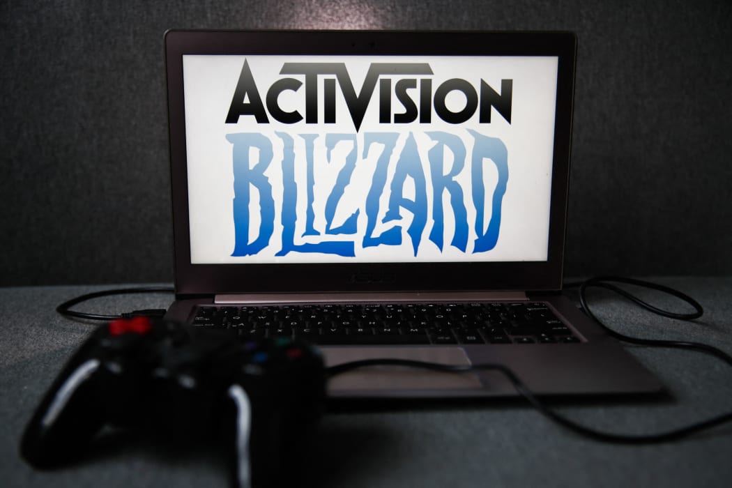 Activision Blizzard logo displayed on a laptop screen and a gamepad are seen in this illustration photo.