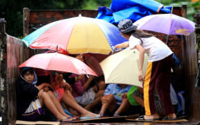 Young Phillipines residents sit in a truck after the local government implemented preemptive evacuations at Barangay Matnog, Daraga, Albay province, due to the approaching typhoon Nock-Ten