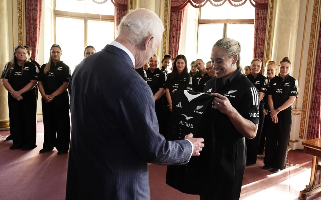 Britain's King Charles III is presented with a gift as he meets with members of New Zealand's Black Ferns rugby team, at Buckingham Palace, 2024.