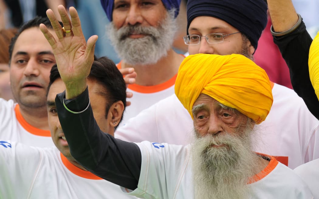 (FILES) Indian-born British national Fauja Singh waves to the media after crossing the finish line in the 10-km event as part of the Hong Kong Marathon on February 24, 2013. Singh, believed to be the world's oldest distance runner, has died in a road accident aged 114, his biographer said on July 15, 2025. (Photo by Dale DE LA REY / AFP)