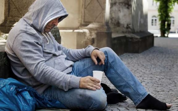 A homeless man begging on the street.