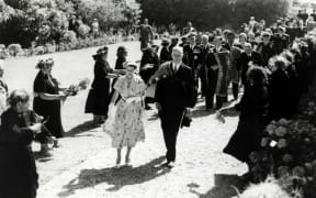 The Queen, escorted by E.B. Corbett, the Minister for Maori Affairs, is welcomed to Waitangi by Māori kuia, 28 December 1953.