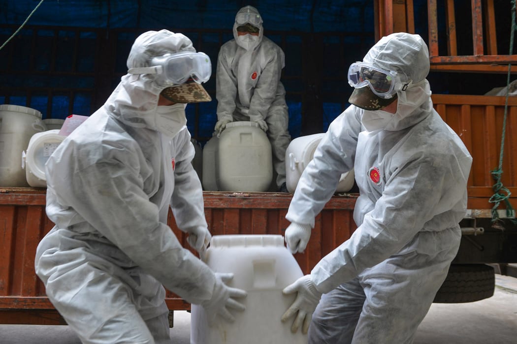 Chinese paramilitary police officers wearing protective gear transfer containers of disinfectant in Yunmeng county, outside Xiaogan City in China's central Hubei province on February 12, 2020. -