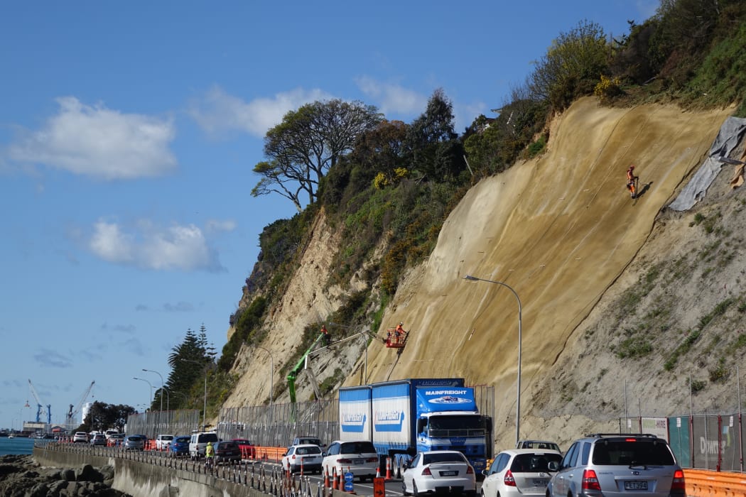 Contractors scale the near vertical slopes of the cliffs above Rocks Road.