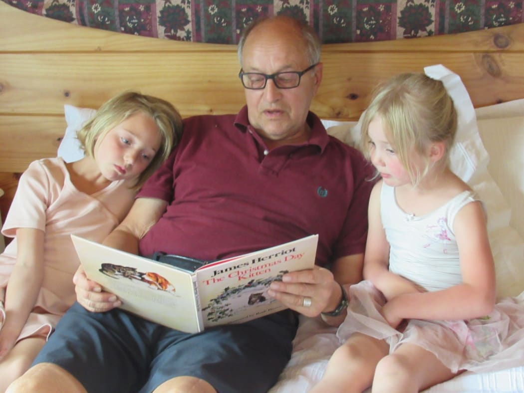Jack Saprunoff, reading to grandchildren Ivy (left) and Zosia Costello.