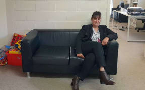 Woman sits on couch with toys at one end