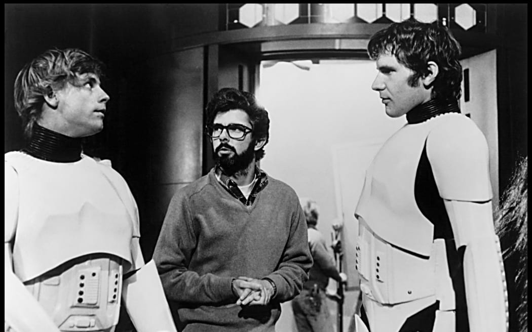 STAR WARS: EPISODE IV - A NEW HOPE. Mark Hamill, George Lucas and Harrison Ford on set.