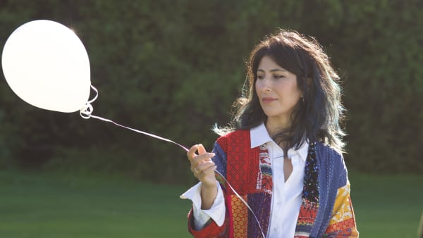 Director Shamin Yazdani holds a while balloon.