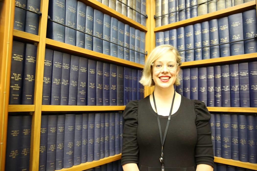 Claire Gilray stands in front of bound copies of Hansard