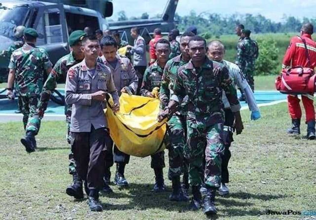 Indonesian soldiers and police carry the body of a colleague killed in Papua.