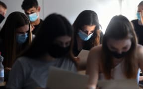 Students of the eleventh grade sit with face masks in a classroom of the Phoenix high school in Dortmund, western Germany, on 12 August 2020, amid the novel coronavirus COVID-19 pandemic.