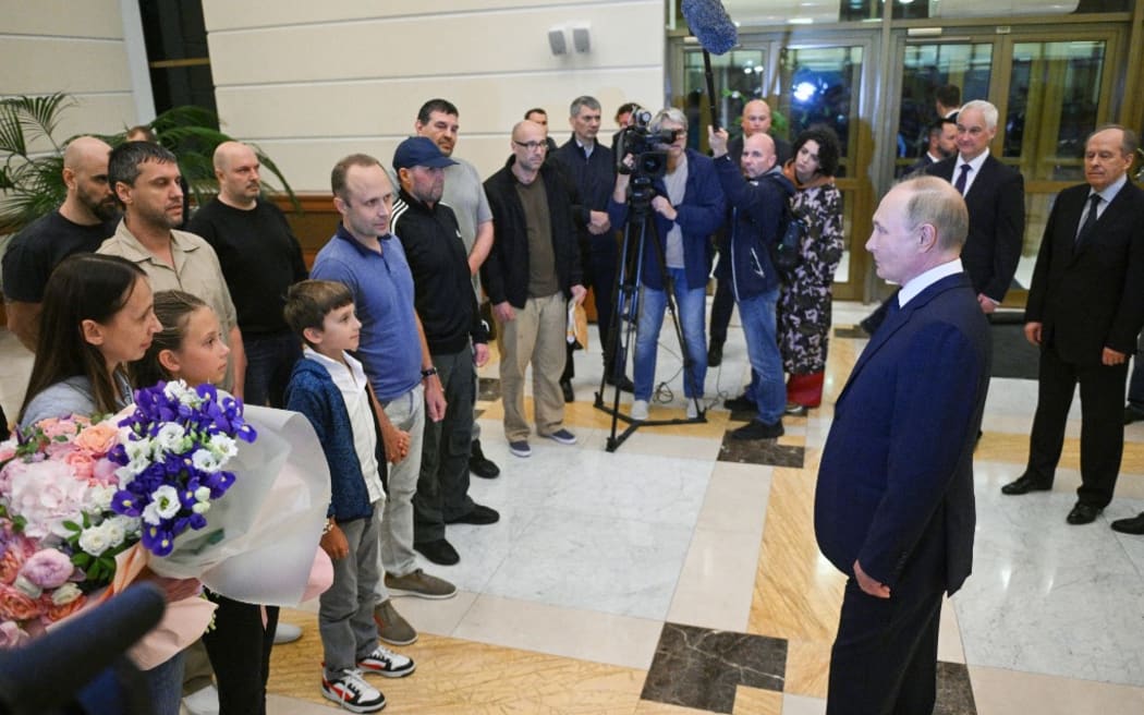 TOPSHOT - In this pool photograph distributed by Russian state agency Sputnik, Russia's President Vladimir Putin welcomes Russian citizens released in a major prisoner swap with the West, at Moscow's Vnukovo airport on August 1, 2024. (Photo by Kirill ZYKOV / POOL / AFP)