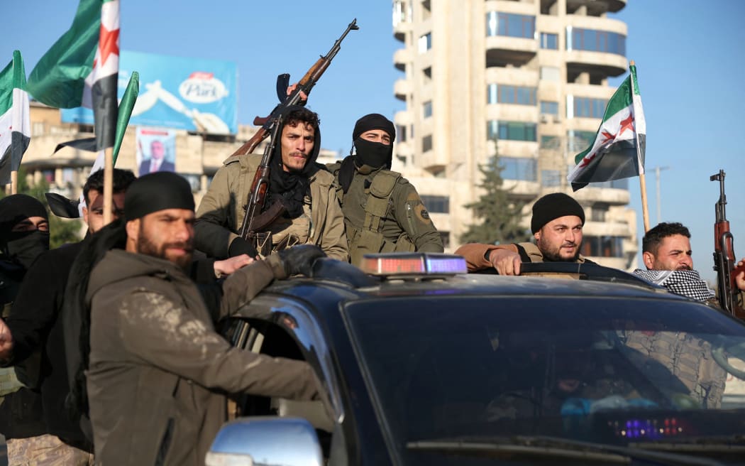 Anti-government fighters brandish their guns as they ride a vehicle in Syria's northern city of Aleppo on November 30, 2024. - Jihadists and their Turkish-backed allies breached Syria's second city of Aleppo on November 29, as they pressed a lightning offensive against forces of the Iranian- and Russian-backed government. (Photo by Omar HAJ KADOUR / AFP)